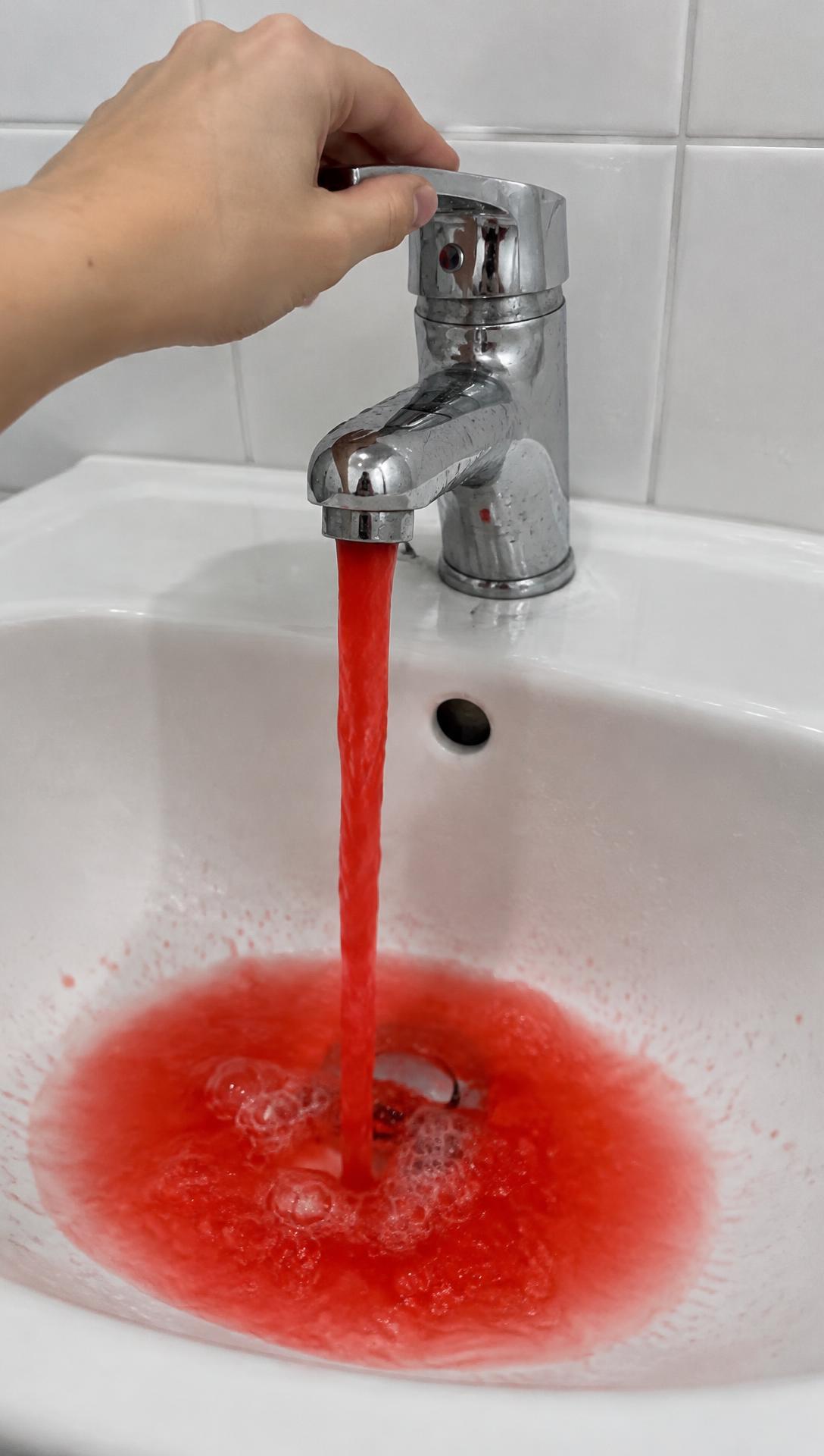 Video still: a faucet running red water as a joke